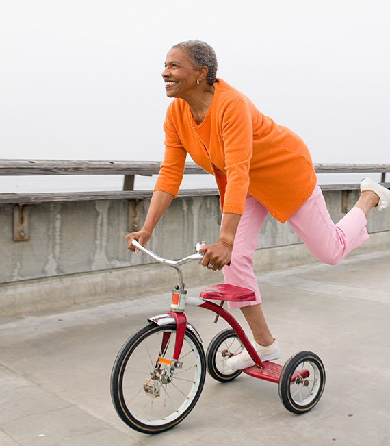 Smiling senior woman playing on a large tricycle